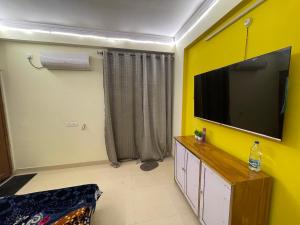 a living room with a flat screen tv on a yellow wall at Cozzy Inn in Bhauli