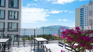 a balcony with tables and chairs and purple flowers at Prague Nha Trang in Nha Trang