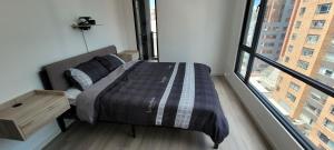 een slaapkamer met een bed en een groot raam bij Nomad-In Luxury Suites and Apartments in Quito
