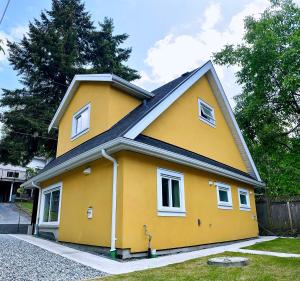 una casa amarilla con techo negro en Vancouver’s Homey Laneway House, en Vancouver