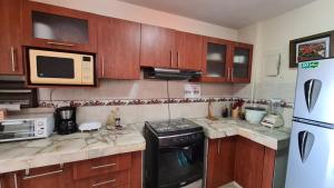 a kitchen with wooden cabinets and a stove and a microwave at Amazing apartment in Salinas, Ecuador in Salinas