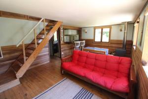 ein rotes Sofa im Wohnzimmer mit einer Treppe in der Unterkunft TuArriendoCL-Acogedora Cabaña Cercana a Playa Niklitschek hasta 5 PAX in Puerto Varas