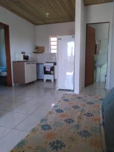 a living room with a kitchen with a refrigerator at Casas do Manoel in Praia do Rosa