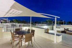 a patio with a table and chairs under a white umbrella at Oriental Beach Pearl Resort in Sam Roi Yot