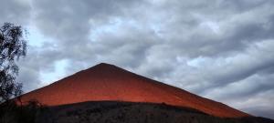 Wielka czerwona piramida pod pochmurnym niebem w obiekcie Cabaña equipada a 300 metros del observatorio mamalluca w mieście Vicuña