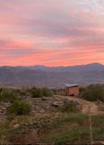 uma casa numa colina com um pôr-do-sol ao fundo em Cabaña equipada a 300 metros del observatorio mamalluca em Vicuña
