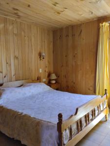 una camera con un letto e una parete in legno di Cabañas Camahueto a Licán Ray
