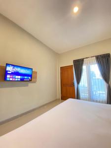 Maluk Stay في Maluk: غرفة نوم مع سرير وتلفزيون على الحائط