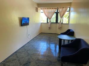a room with a tv and two chairs and a table at Apartamento na praia da tabuba com vista mar in Caucaia