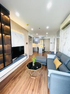 een woonkamer met een blauwe bank en een flatscreen-tv bij Amy Apartment Hue in Hue