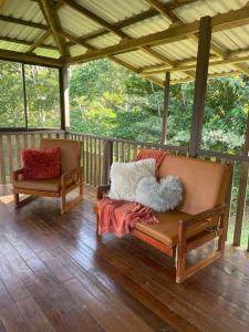 2 sillas sentadas en un porche con suelo de madera en Amazilia, en Heredia