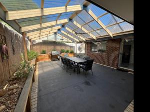 a patio with a table and chairs under a roof at Beach Haven in Rosebud