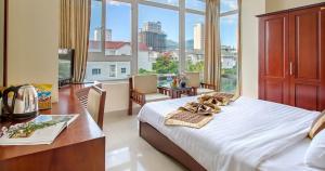 Schlafzimmer mit einem Bett, einem Schreibtisch und einem großen Fenster in der Unterkunft Sunview Beach Hotel Danang in Đà Nẵng