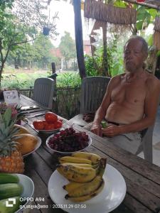 a man sitting at a table with plates of fruit at Monyharch Angkor Homestay, in Phumĭ Kngan Pông +31 photos