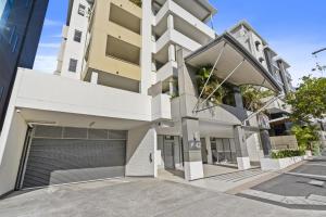 an exterior view of a white building with a garage at Modern 2BR Apt next to SouthBank Free Wifi & Pool in Brisbane