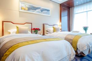 two beds in a hotel room with white and gold sheets at 潍坊富华大酒店a座 in Weifang