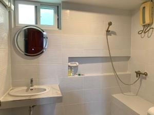 Baño blanco con lavabo y espejo en Priew Wan Guesthouse, en Patong Beach