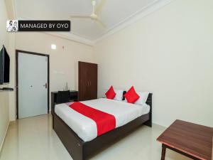 a bedroom with a bed with red pillows and a table at Super Collection O Jagadamba Near Beach Road in Visakhapatnam