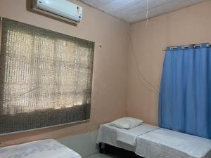 a room with two beds and a window with a blue curtain at Cantinho do amor in Vitória