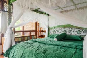 a bedroom with a green bed with a canopy at Harum Manis Cottages in Jepara