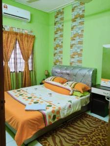 Cama en habitación con paredes verdes en Syukur Homestay Ipoh en Ipoh