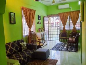 a living room with green walls and a couch and chairs at Syukur Homestay Ipoh in Ipoh