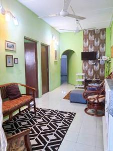 Syukur Homestay Ipoh في ايبوه: غرفة معيشة مع كراسي وجدران خضراء