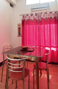 stół jadalny z czerwonymi krzesłami i różową zasłoną w obiekcie Panchalaya Homestay w mieście Guwahati