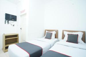 two beds sitting in a room with a tv at Hotel Bhakti Syariah in Padang +26 photos