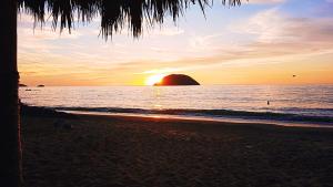a sunset on the beach with the sun setting at La Casita de Cayita in La Peñita de Jaltemba