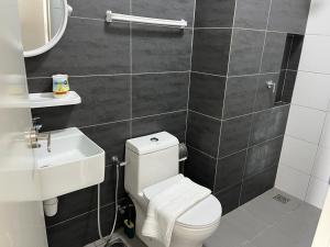 La salle de bains est pourvue de toilettes blanches et d'un lavabo. dans l'établissement horizon suite 25-11, à Sepang