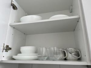 a white cabinet with plates and bowls and glasses at horizon suite 25-11 in Sepang