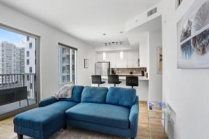 a blue couch in a living room with a large window at Sunset Views from a Stylish 1BR High Rise in Tampa in Tampa