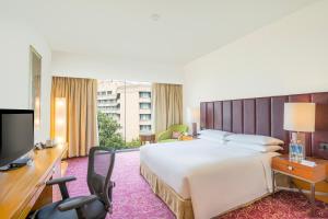 a hotel room with a large bed and a television at Courtyard by Marriott Hyderabad in Hyderabad