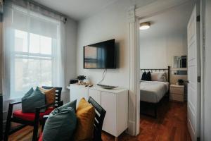 ein Schlafzimmer mit einem Bett und einem TV an der Wand in der Unterkunft HRésidences Cozy Heritage St André Apt Mtl in Montreal
