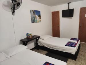 Habitación con 2 camas, mesa y TV. en Absolute Hotel & Hostel Boutique en Medellín
