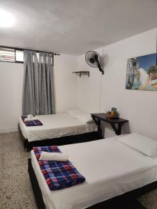 een kamer met 3 bedden en een tafel met een ventilator bij Absolute Hotel & Hostel Boutique in Medellín
