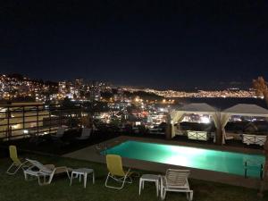 a swimming pool at night with a view of a city at FINTUPS SPA in Viña del Mar