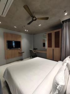 1 dormitorio con cama blanca y ventilador de techo en Playotel Inn Aria, Bhopal, en Bhopal