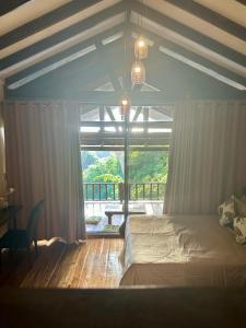 a bedroom with a bed and a large window at TukoKubo in El Nido
