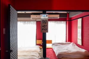 two beds in a room with red walls at Geisha Expelience Stay in Tokyo