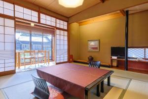 una sala da pranzo con tavolo e TV di Kinosaki Yamamotoya a Toyooka