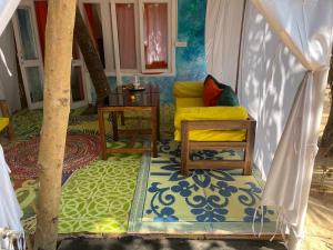 a living room with a yellow couch and a table at Art Resort Goa in Palolem