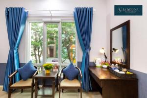 胡志明市的住宿－La Serena Boutique Hotel，客房设有书桌和带蓝色窗帘的窗户。