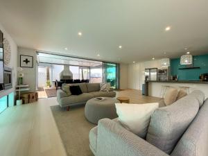 a living room with two couches and a kitchen at Luxury Beachside Retreat in Papamoa
