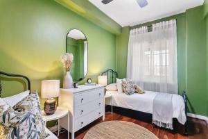 a green bedroom with two beds and a mirror at Vintage 2BR CBD Apartment w/River View in Perth