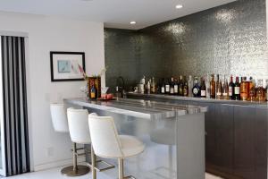 Skyline Serenity Luxe Suite-Private Room في لوس أنجلوس: بار وكراسي بيضاء وطاولة بزجاجات
