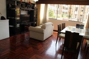 uma sala de estar com uma cadeira branca e uma mesa em Hermoso departamento de dos dormitorios en el primer piso em Lima