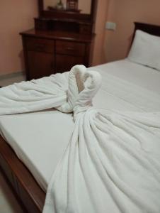 a white towel laying on a white bed at Ajith Putha Grand in Madampe