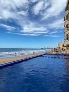 a swimming pool next to a beach with the ocean at Marina del Sol Resort Condo directly on the Ocean 102 in Mazatlán